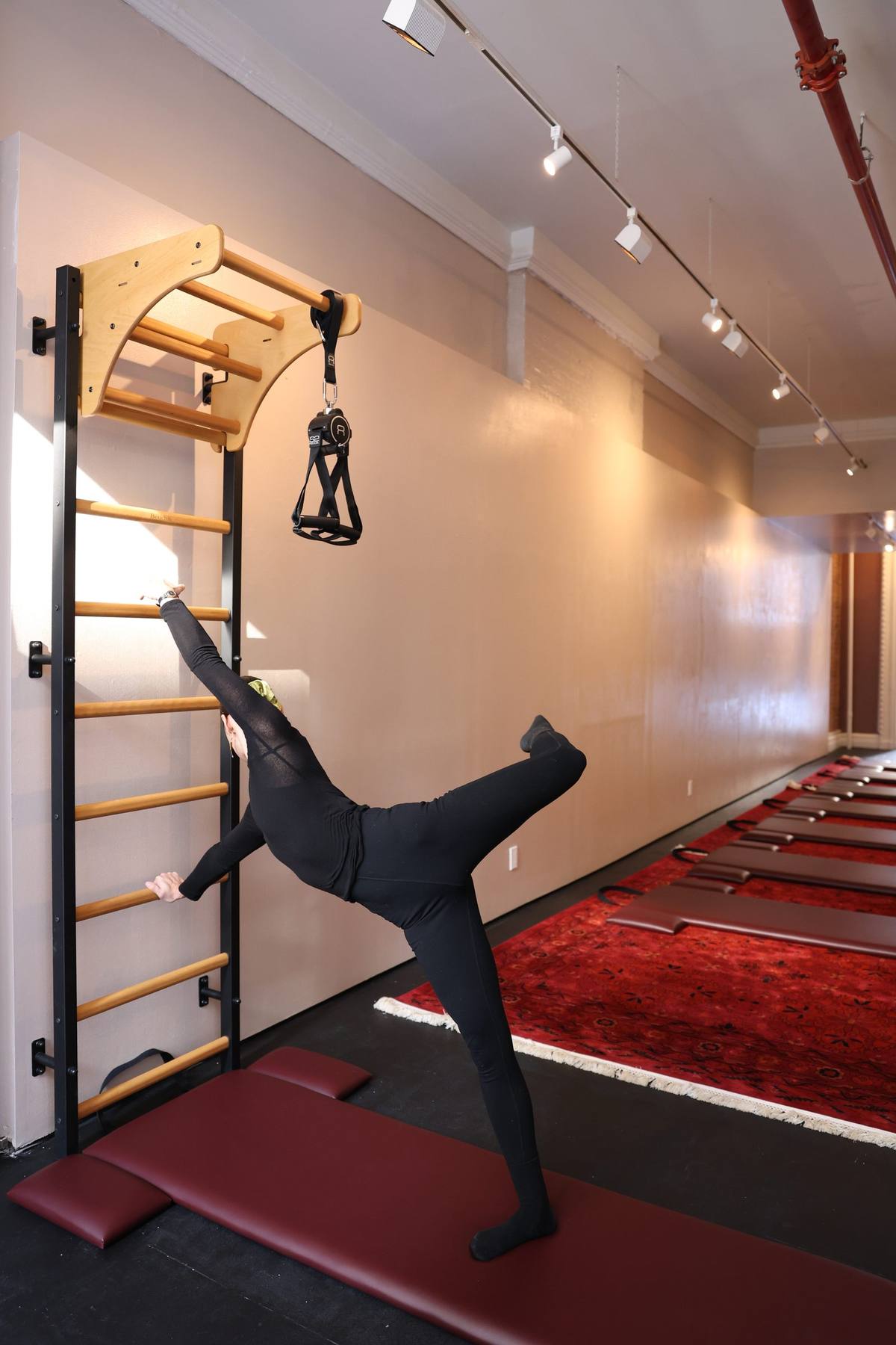 Dynamic wall bar exercise at Praxis Pilates demonstrating suspension training
